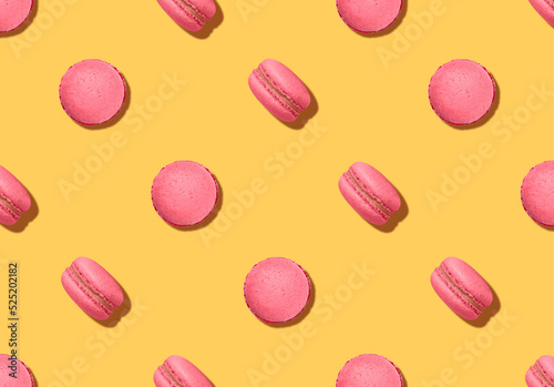 Pattern with almond cookies. Pink colored macaroons on bright yellow backdrop