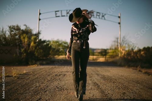 Woman posing in front of a ranch in western fashion and cowboy hat