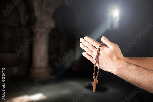 Closeup of praying hand holding the wooden cross.