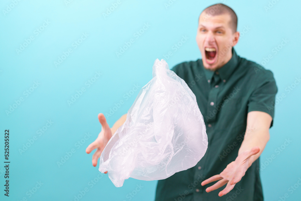 Naklejka premium A surprised man with an open mouth holding his hands above a flying plastic bag on a blue background. Free. Faces. Future. Disagree. Gesture. Bad. Rude. Surprised. Plastic Bags. Wondering. Amazed