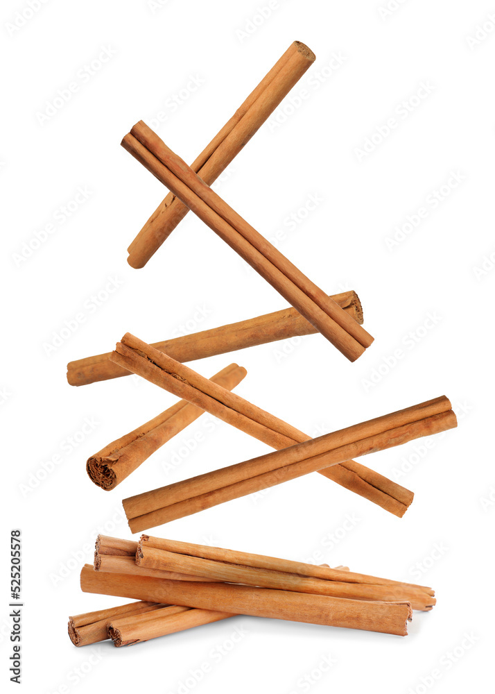 Aromatic dry cinnamon sticks falling on white background Aromatic dry cinnamon sticks falling on white background