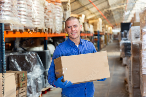 Portrait of loader with a large box in his hands in a store warehouse