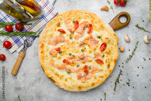 Pizza with salmon and anchovies with tomatoes on grey table top view