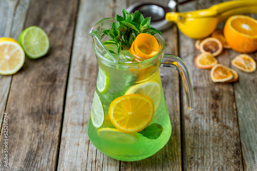 green Citrus lemonade with orange, lemon and lime on wooden table