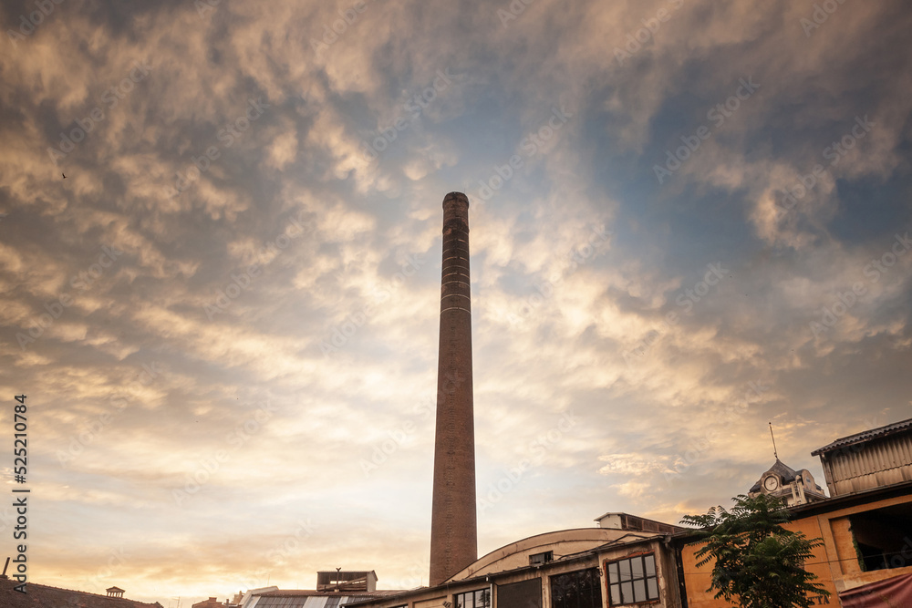 Selective blur on Broken Red brick chimney from an abandoned factory at dusk, with sun, dating back from the industrial revolution in a bankrupted industry.....