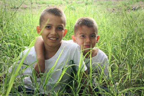 two children sitting and embracing on tall grass © Diego