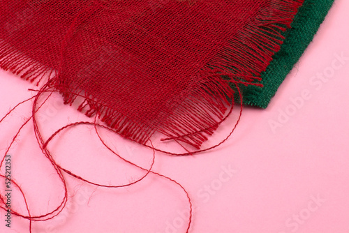 Fototapeta Frayed green and red burlap fabric pieces on pink background