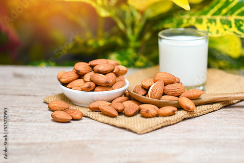 Almond milk and Almonds nuts on white bowl with green leaf on sack background, Delicious sweet almonds on the wooden table , roasted almond nut for healthy food and snack