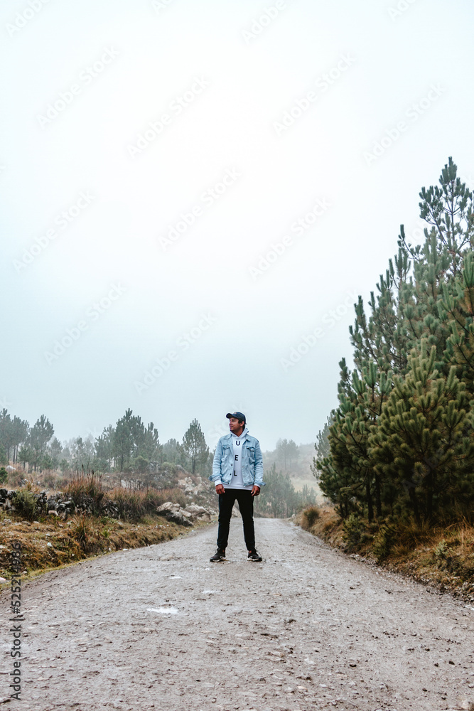 Obraz premium man standing in the middle of a dirt road with cloudy and cold environment