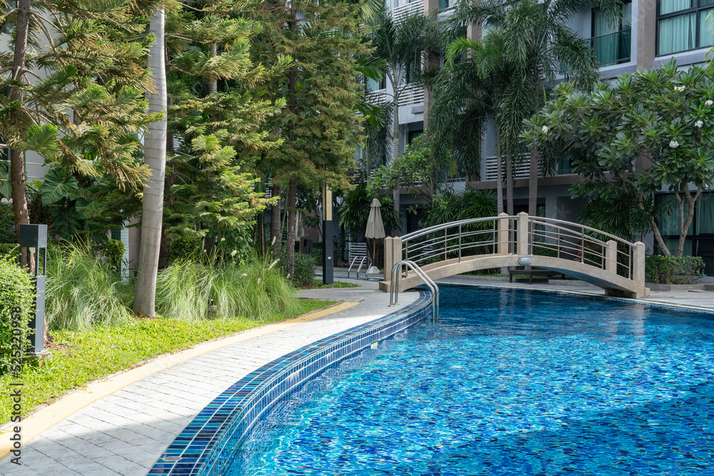 A small arch bridge spans the blue water pool in the condominium.