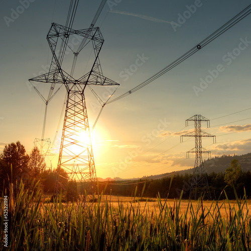 High Voltage Power Transmission Lines on Towers During Golden Sunset in Rural Oregon Over Fields Near Road photo