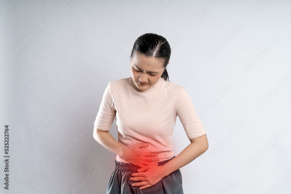 Asian woman was sick with stomach ache putting her hands on belly with red spot. Asian woman was sick with stomach ache putting her hands on belly with red spot.