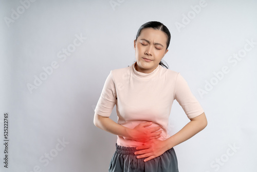 Asian woman was sick with stomach ache putting her hands on belly with red spot.
