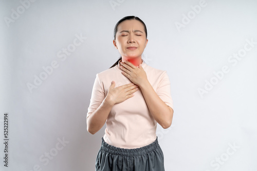 Asian woman was sick with sore throat and touching neck with red spot, standing isolated on white background.
