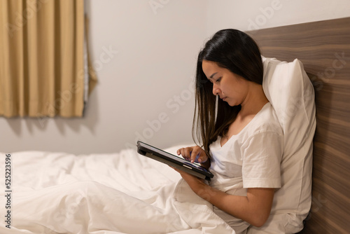 Asian women are using the tablet on the bed.