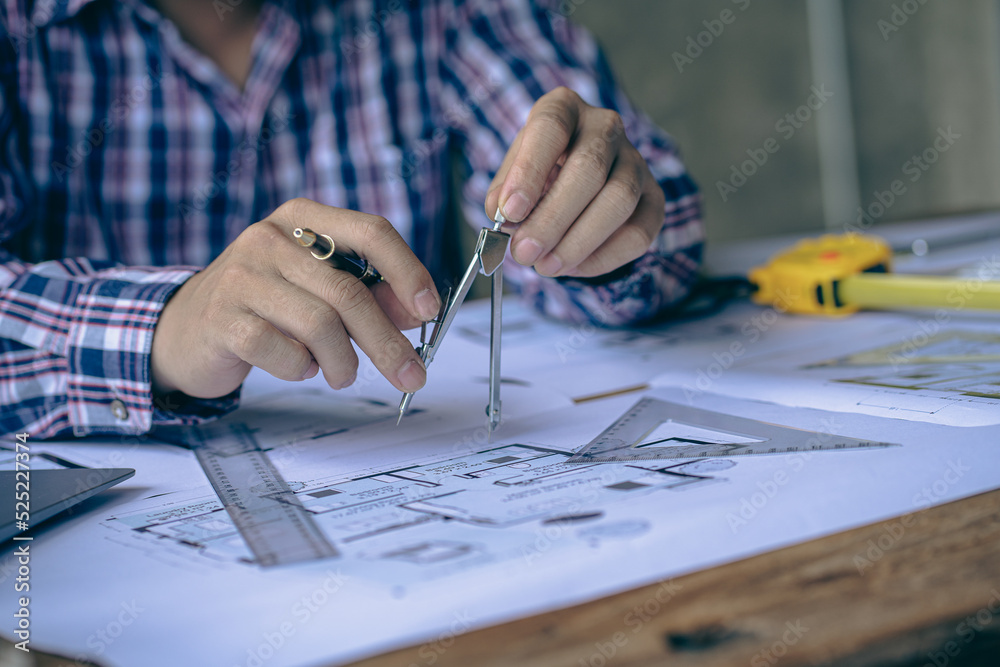 An engineer or architect working on a new project on a construction site. With blueprints and using a laptop draw a project design in the concept of an architectural engineer. An engineer or architect working on a new project on a construction site. With blueprints and using a laptop draw a project design in the concept of an architectural engineer.