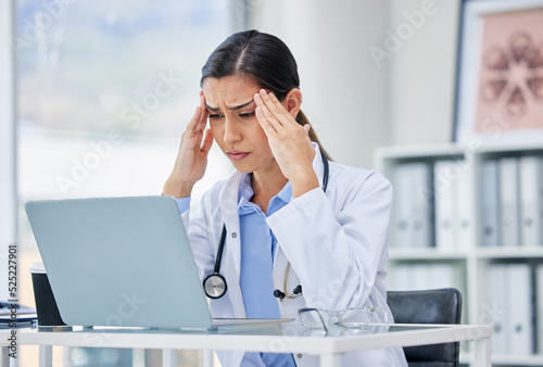 Stress or burnout with doctor thinking and working on laptop in hospital consulting room or office. Medical healthcare worker or specialist surgeon with anxiety headache from mental health issues photo