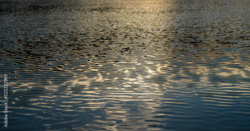 ฺBeautiful Reflected the sun rays hitting the water surface river is waves the sea surface before sunset natural background.