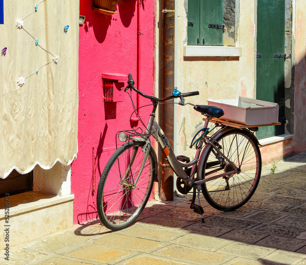 Bicycles parked in front of a colorful house in Burano island, Italy.