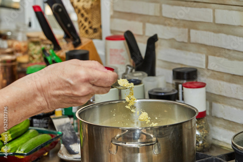 Chef tosses the chicken broth powder into pot on gas stove