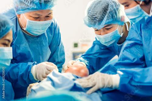 Professional anesthesiologist doctor medical team and assistant is performing baby cesarean section and hold the baby giving birth with surgery equipment in modern hospital operation room photo