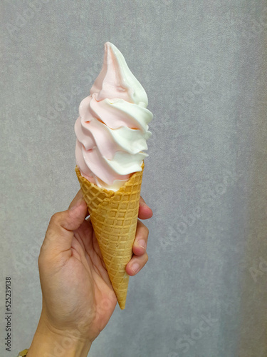 hand holding strawberry and vanilla ice cream mix on wall background
