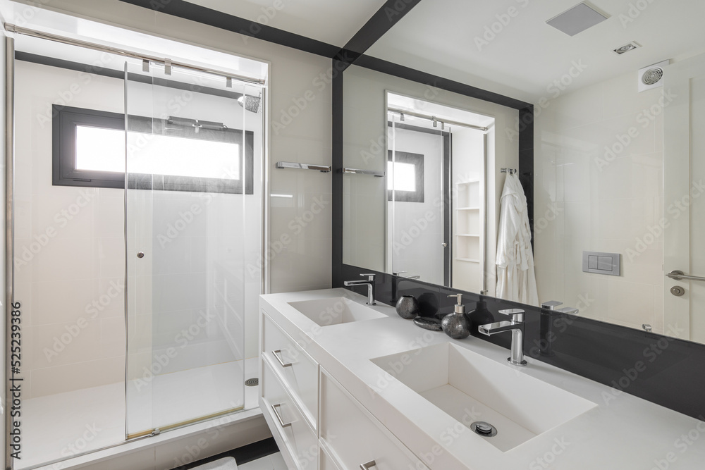 White bathroom with shower, two sinks and black frame mirror. Modern interior of refurbished apartment. White bathroom with shower, two sinks and black frame mirror. Modern interior of refurbished apartment.