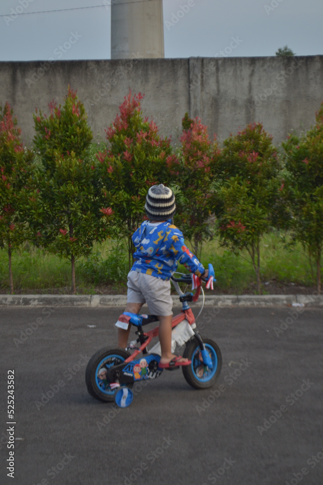 Bandung 20 August 2022 - Potrait of young boy playing with his tricycle in the dusk Bandung 20 August 2022 - Potrait of young boy playing with his tricycle in the dusk