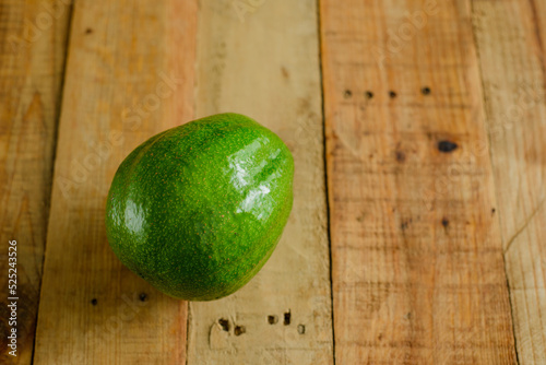 Avocado on wooden table. Isolated avocado in foreground.