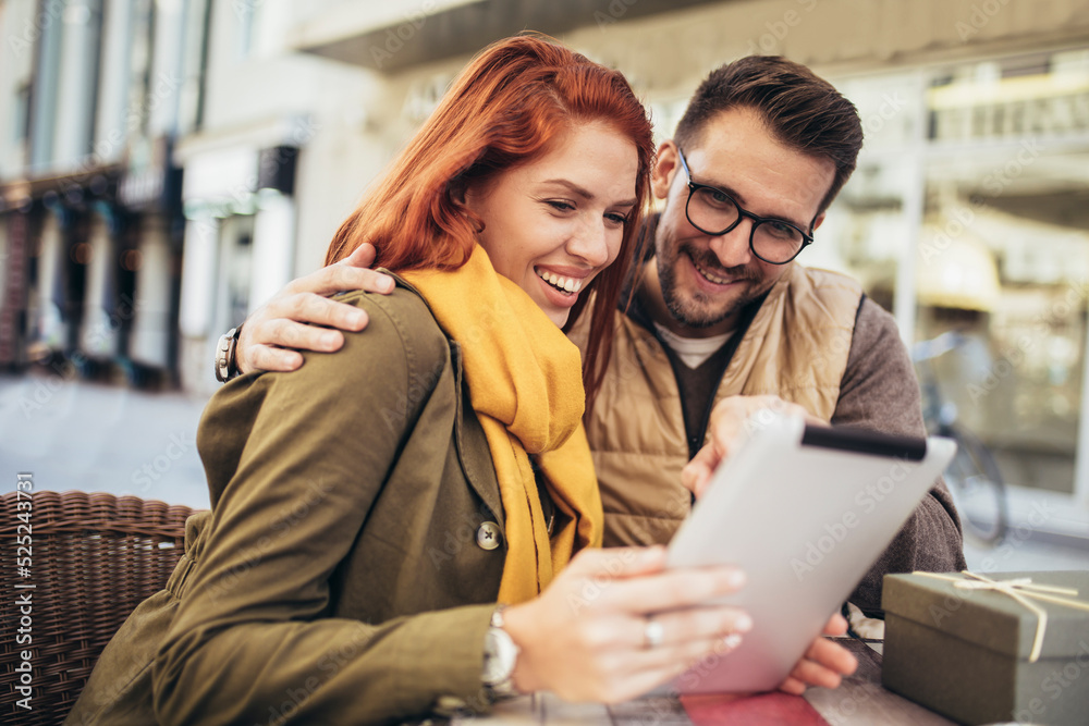 Happy young couple using a digital tablet together at a coffee shop.