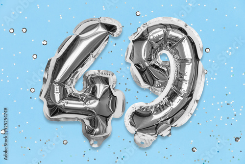 Silver foil balloon number, digit forty nine on a blue background with sequins. Birthday greeting card with inscription 49. Top view. Numerical digit. Celebration event, template. photo