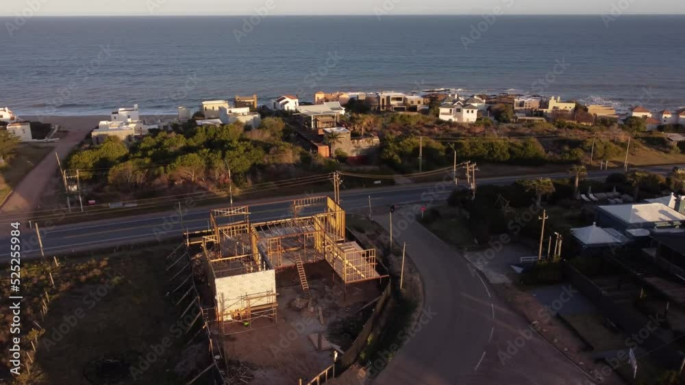 Aerial circle shot showing construction site of new build villa in Punta del Este during sunset Aerial circle shot showing construction site of new build villa in Punta del Este during sunset