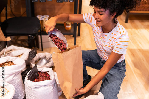 Happy black woman filling paper bag with beans photo