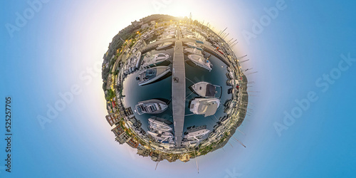 Aerial 360 tiny planet of Porto Vecchio city harbor at night in Corsica island of France. Drone view of downtown skyline with the boats and yachts in port in the Mediterranean sea after sunset.