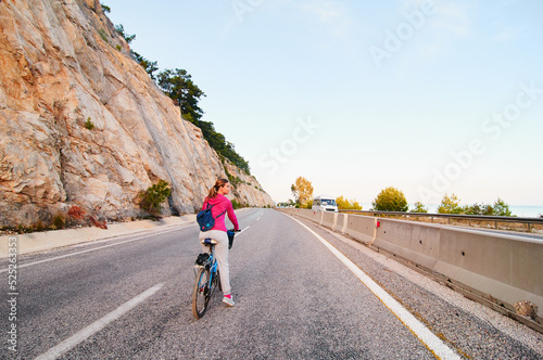 Hobby and leisure. Young woman riding bicycle by the road way.