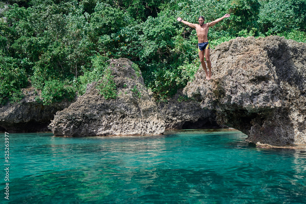 Vacation and activity. Man jumping on blue tropical lagoon, Siargao Island, Philippines.
