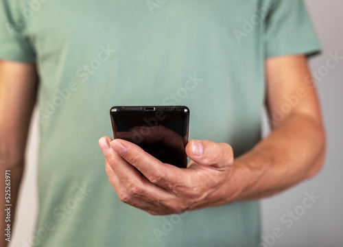 Man hand holding phone. Male looking at smartphone screen for video call or reading message, checking weather, bank balance, surfing Internet