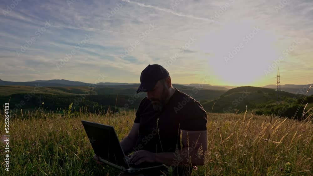 Man with laptop sitting and networking in the country Man with laptop sitting and networking in the country