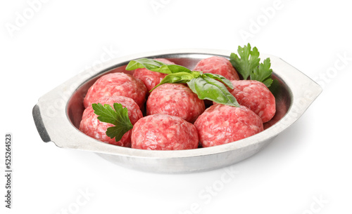 Dish with raw meat balls, parsley and basil on white background