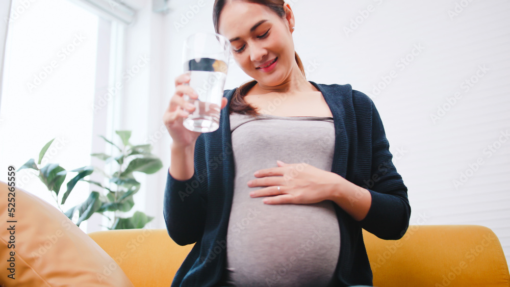 Asian pregnant woman drinking water on the sofa at home. Asian pregnant woman drinking water on the sofa at home.