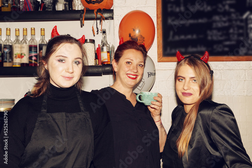  Smiling happy middle aged woman owner of a cafe and her professional baristas team. Coffee Shop, Bar, Counter, Cafe Concept. Young entrepreneur. Halloween bakering. Preparing for Halloween party. photo