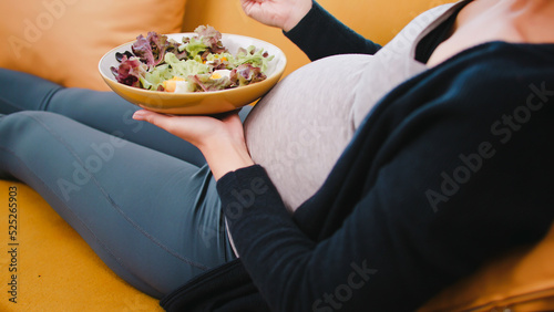 Happy Asian pregnant woman eats healthy food for her unborn baby.
