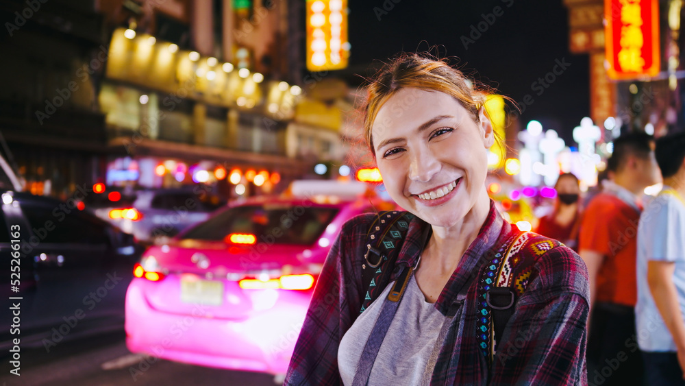 Portrait of a beautiful woman standing and smiling on the street of city at night.