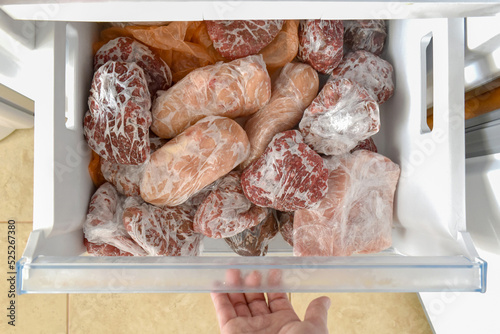 Frozen meat with plastic wrap or cling film in a the freezer.  How to freeze fresh meat concept.  photo