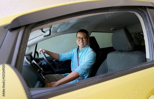 Asian man smiling to the camera from inside his car