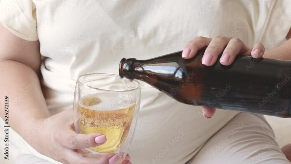 pregnant woman pour beer from bottle to glass.big advanced belly in
