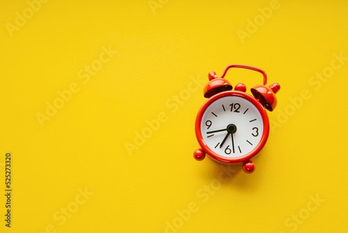 Red alarm clock on a yellow paper background. Minimalistic image