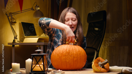 Preparing pumpkin for Halloween. Pulling out guts and seeds and being grossed out by it. Woman sitting and carving halloween Jack O Lantern pumpkin at home for her family.