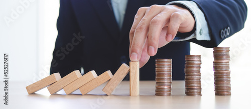 Protection finance from domino effect concept. Hands stop domino effect before destroy stack of money. photo