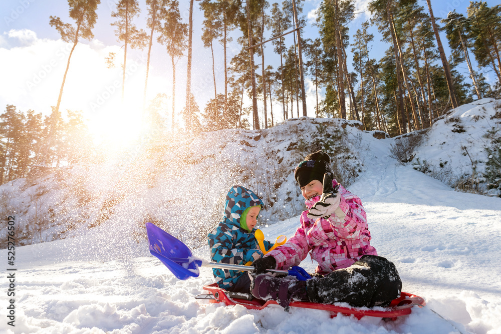 Portrait of two cute adorable little playful children wearing warm snow jacket enjoy having fun playing at park outdoors on sunny cold day. Winter christmas holidays leisure time activities outside